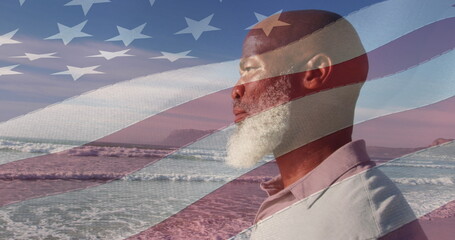 Image of flag of united states of america over senior african american man on beach