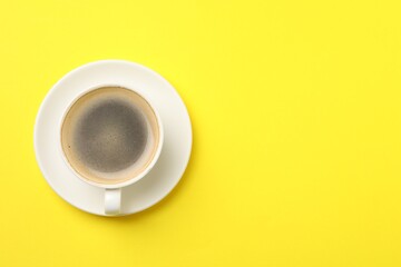 Aromatic coffee in cup on yellow background, top view. Space for text