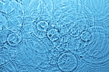 Rippled surface of clear water on light blue background, top view