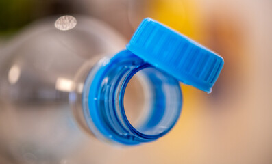 Close-up of Blue Tethered Bottle Cap on Clear Plastic Bottle, New EU Regulation Compliance, Focus on Environmental Impact