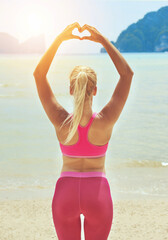 Fitness, yoga and heart hands with woman on beach for wellness, mental health or exercise in...
