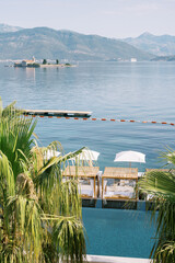 Sun loungers stand on the shore of the Tivat Bay overlooking the island of Gospa od Milosti....