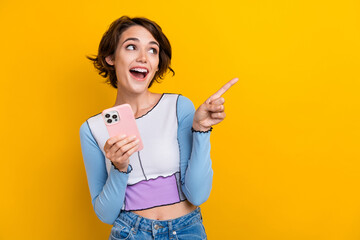 Photo of excited funky lady dressed shirt chatting modern gadget showing looking empty space isolated yellow color background