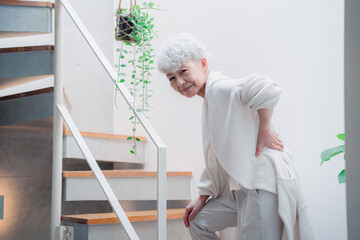 階段で腰痛に苦しむ高齢の女性