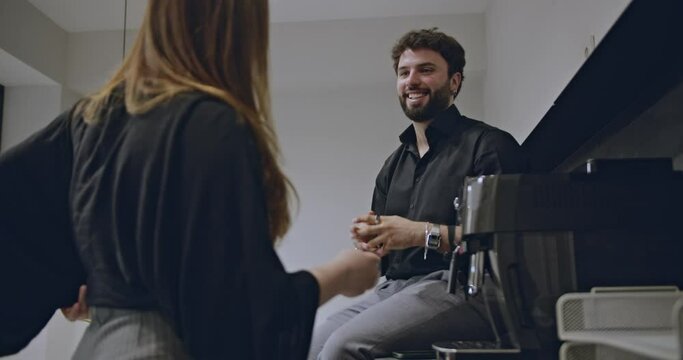 A joyful couple embracing and enjoying coffee in a contemporary kitchen space, showcasing warmth and happiness.