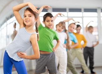 Dynamic little girl training in dancehall with trainer and other attendees of dancing courses