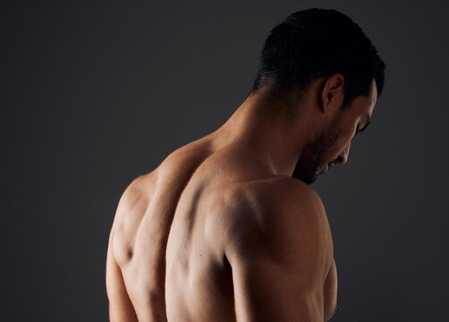 Sexy, muscle and back of man for exercise with workout, gym aesthetic and results for fitness goals in studio. Topless guy, bodybuilder and strong body with shoulder training by black background