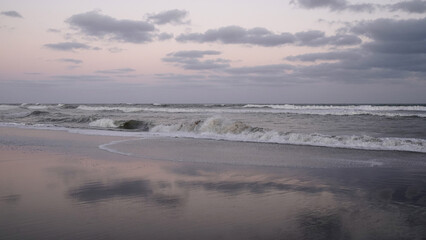 Enchanting view of the sea shore under a magical sunset sky.  The sky reflects in the wet sand.