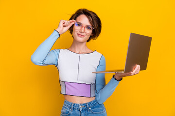 Portrait of lovely intelligent girl touch eyeglasses hold laptop coworking isolated on yellow color...