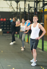 Strong young man practicing with kettlebell in exercise room during weight training classes