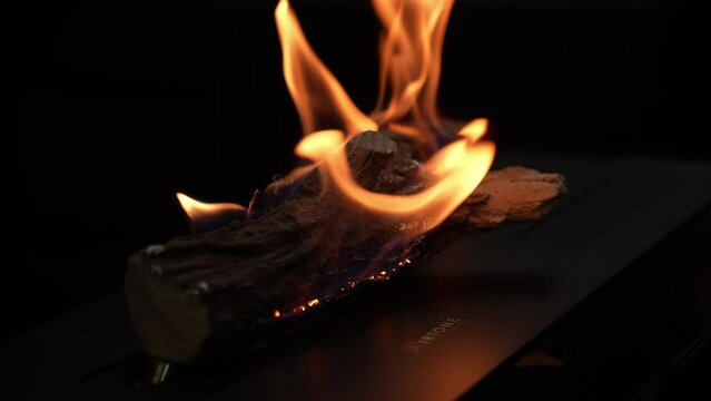 Burning firewood log with vibrant flames, providing heat and warmth for a cozy atmosphere