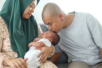 Portrait of lovely muslim mother hold her newborn baby and father kissing his baby's forehead