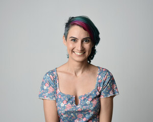 a close up head and shoulders portrait of young alternative female model, with pink and grey shaved undercut hair style, wearing a floral blue top. dramatically pulling expressive facial expressions. 