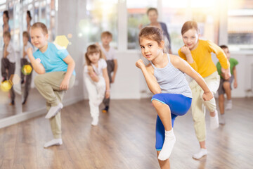 Obraz premium Happy positive smiling preteen boys and girls practicing dance, with female trainer in dance hall