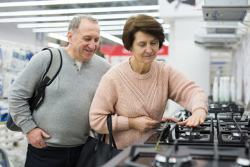Mature couple choose a gas stove in an electronics and home appliance store to buy it