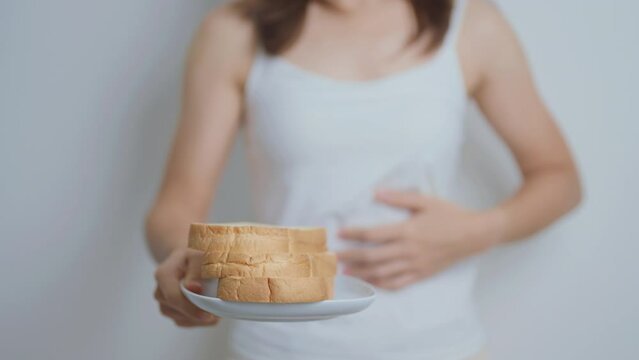 Gluten intolerance, Gluten free and celiac disease or wheat allergy concept. woman hold Bread and having abdominal pain after eat gluten. stomach ache, Nausea, Bloating, Gas, Diarrhea and Skin rash