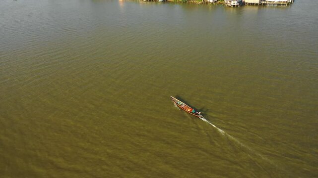 Aerial view circling a classic Kolae boat on a river in Surat Thani, Thailand