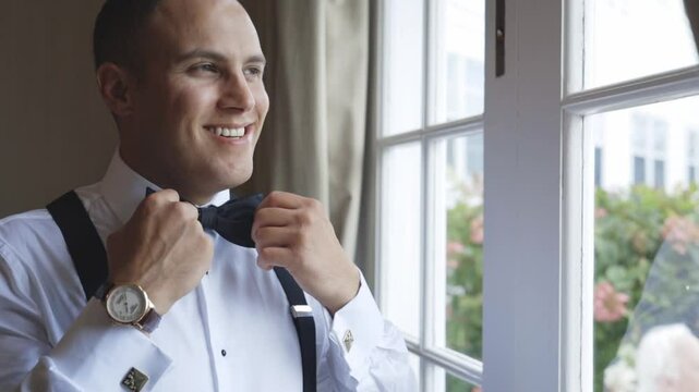Man adjusts his bowtie happily