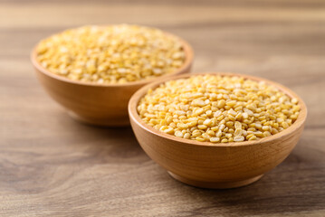 Yellow peeled split mung bean in bowl on wooden background, Food ingredient