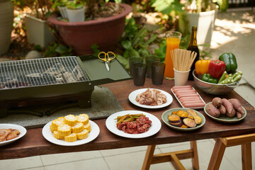 Plates with raw meat and vegetables prepared for barbecue