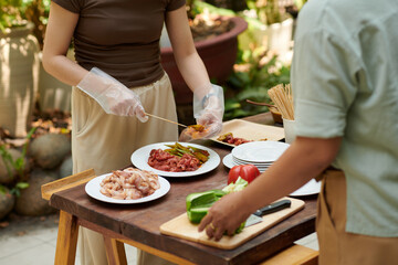 Couple cooking kebabs outdoors for family party