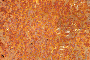 A close-up of a heavily rusted metal surface, showcasing a textured pattern of orange, brown, and red hues with various pitted and corroded areas.