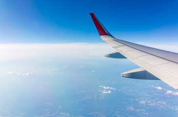View from the airplane window at a beautiful cloudy sky and the airplane wing