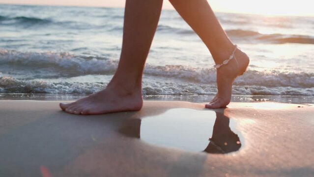 woman walks barefoot on the beach and walks near the sea. legs of a young beautiful tanned girl at sunset sun rays. A weekend getaway to the great outdoors. travel and adventure. Summer mood.
