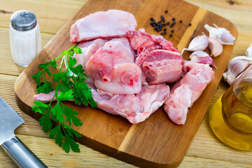 Chopped fresh raw rabbit with greens, garlic and spices prepared for cooking on wooden cutting board. Healthy dietary food