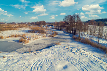 Aerial view of the countryside and frozen winding brook on a sunny day. Beautiful nature landscape