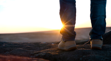 Man in hiking boots at top of cliff admiring awesome spectacular mountain view close-up