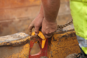 Hands of Banksman fixing lifting chain to trench support box