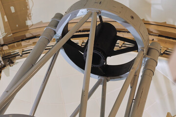 Large telescope positioned inside a modern observatory with white interior walls and ceiling