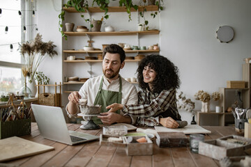 Fototapeta premium Bearded mature man and woman vlogger sculpt vases and bowls from clay in studio, recording content for online courses or social media.