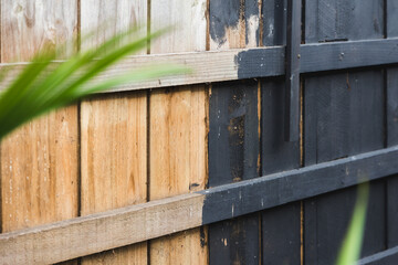 half painted backyard retaining wall or fence, charcoal vs bare wood, home improvement and renovation