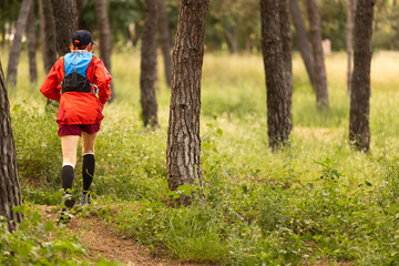 Fototapeta premium A woman in a red jacket and black hat is kneeling down and tying her shoes. She is smiling and she is enjoying herself