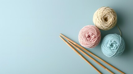 Three balls of thread and wooden bamboo knitting needles on light blue background. Hobby, relaxation, mental health, sustainable lifestyle 