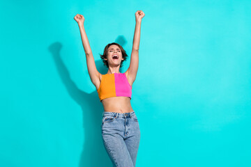 Photo of lucky cool woman wear pink orange top shouting yeah rising fists empty space isolated teal...