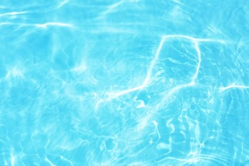 Fototapeta premium Blue water with ripples on the surface. Defocus blurred transparent blue colored clear calm water surface texture with splashes and bubbles. Water waves with shining pattern texture background.