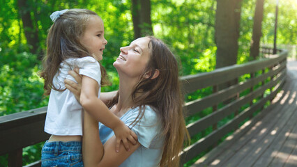 Naklejka premium Mother and daughter have fun in the park. Happy family concept. Beauty nature scene with family outdoor lifestyle.