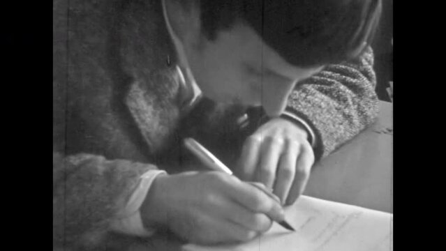 Close up, man student cheating on exam test in university classroom. Man cheater sitting at class desk, using cheat sheet, writing in college lesson. Vintage black white movie. Retro education 1980s