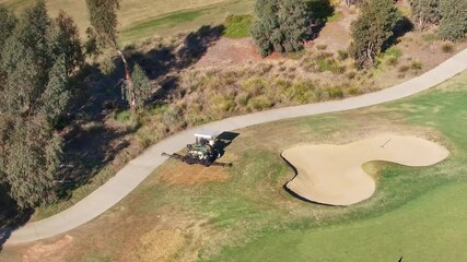 Aerial view of golf course maintenance with spraying equipment
