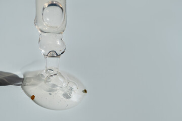 A drop of cosmetic aromatic oil drips from the pipette. Front view.