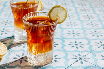 Trendy summer drink espresso tonic on blue tile background with shadow of sun. Cold coffee cocktail...
