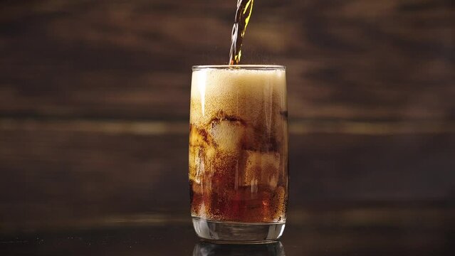 Pouring Cola with ice cubes. Cola with Ice and bubbles in glass.