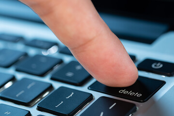 Finger of the computer user, he presses the delete button on the computer keyboard	