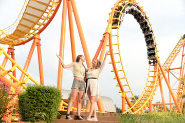 Two pretty teenage girls have fun at theme park on weekend, beautiful young friend teenager enjoys...