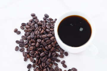 淹れたてで香りのよいコーヒーが入ったカップと、コーヒー豆
