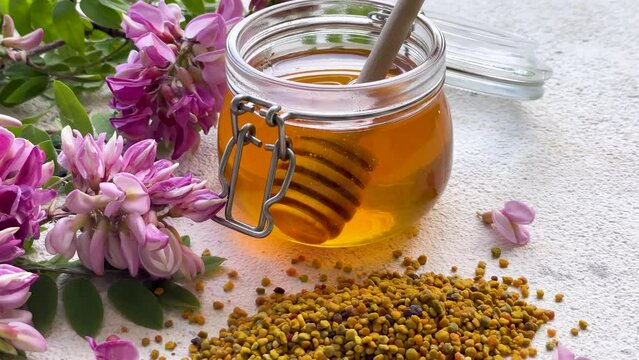 Raw organic bee pollen and honey in jars  and acacia flowers.