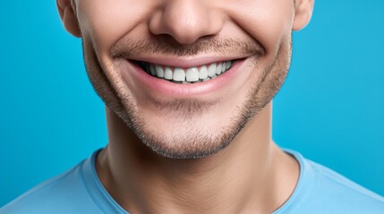 Fototapeta premium Close-up of a man's smiling face with perfect white teeth and stubble on a blue background. Happy expression and dental health concept.